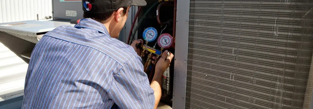 HVAC technician servicing a condenser unit in Barling