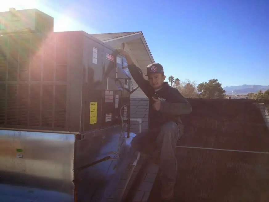 HVAC technician performing Air Duct Cleaning on a rooftop unit in Barling